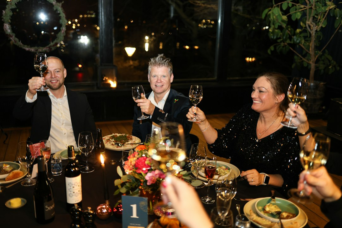 Adult guests in evening wear raising glasses beside a themed event table